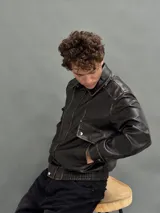 Campera estilo bomber de cuero sintético con efecto desgastado, cuello camisero, cierre frontal con botones a presión y puños y cintura elásticos.