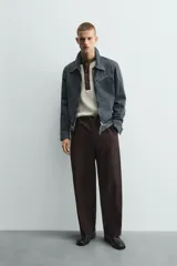 Cazadora cropped fit de denim de algodón, color negro lavado. Presenta cuello solapa, manga larga con puños abotonados, cierre frontal de cremallera y bolsillo superior con cierre de cremallera en el pecho.