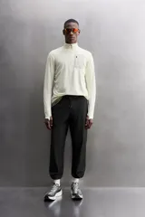 Camiseta de manga larga negra, confeccionada en tejido técnico ligero y elástico. Tiene cuello alto con cremallera, corte slim fit, bolsillo frontal con cremallera y puños con cinta a contraste.