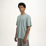 Remera celeste de corte holgado con bolsillo en el pecho y logo estampado en color naranja.