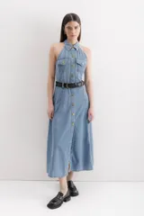 Vestido midi de denim celeste, con cuello camisero halter, botones dorados en el frente, bolsillos en el pecho y falda acampanada.