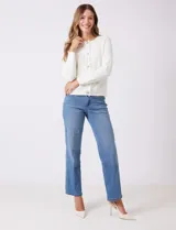 Cardigan de punto color fucsia, con escote a la base, cierre frontal con botones metálicos dorados y terminaciones desflecadas. Presenta bolsillos simulados en la parte delantera y mangas largas.