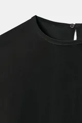 Blusa de cuello redondo y manga larga, confeccionada en tejido fluido con acabado satinado. Presenta un diseño de corte holgado, bajo recto y cierre en la espalda mediante una pequeña abertura con botón.
