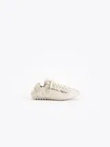 Zapatillas urbanas de cuero vacuno en color beige, con detalles de volados en los laterales de los cordones y suela de goma plana con textura.