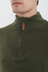 Sweater verde oliva de tejido acrílico con textura similar al cashmere, corte clásico, cuello alto con cierre metálico y tirador de cuerina ecológica.