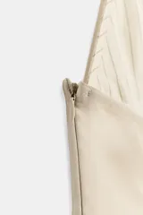 Vestido corto con escote halter pronunciado y hombros descubiertos, de color beige en la parte inferior y diseño a rayas con volantes en la parte superior.