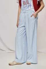 Pantalón de tiro alto con silueta amplia y caída fluida, confeccionado en tejido celeste con textura a rayas finas. Cuenta con cintura elástica con lazo de ajuste y bolsillos laterales.