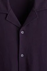 Camisa de manga corta en punto jacquard de mezcla de algodón, color morado, con cuello abierto y cierre frontal de botones.
