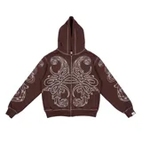 Hoodie con cierre frontal, color marrón, con diseño estampado de hojas de acanto en color blanco que recorre el frente y las mangas. Cuenta con bolsillos laterales y costuras visibles.