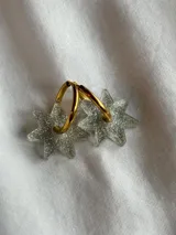 Aros tipo argolla dorada con dije colgante en forma de estrella de acrílico color rosa.