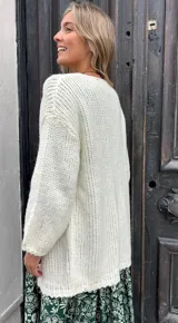 Saco abierto de punto grueso en color crudo, con mangas largas y diseño holgado sin botones.