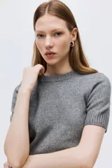 Buzo de punto de manga corta con cuello redondo y ajuste entallado. Presenta terminaciones acanaladas en cuello, puños y ruedo.