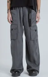 Pantalón cargo de corte oversize y pierna recta, color grafito. Cuenta con cintura elastizada, cinturón integrado con cinta de seguridad, múltiples bolsillos laterales con solapa y detalles reflectivos.