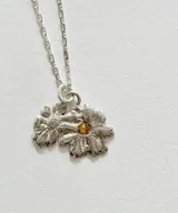 Collar de plata con cadena eslabonada y dije doble de flores con un cristal amarillo en el centro.