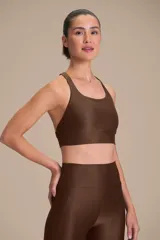 Top deportivo de compresión media con diseño de espalda cruzada y breteles finos. Confeccionado en tejido acanalado con un acabado de brillo sutil, cuenta con copas removibles y tecnología de ajuste adaptable.