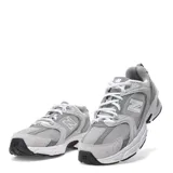 Championes urbanos New Balance modelo 530, color gris con detalles en blanco y negro, confeccionados en malla transpirable y capas superpuestas de material sintético. Cuentan con el logotipo "N" en los laterales y entresuela con tecnología ABZORB.