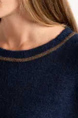 Sweater de tejido de punto con calce oversize, color azul marino con detalles en color marrón en las mangas y cuello. Presenta un diseño de manga larga y puños y ruedo acanalados.