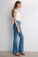 Jeans de tiro medio con corte bootcut y ajuste slim. Presenta diseño de cinco bolsillos, trabillas en la cintura y cierre frontal con cremallera y botón. Incluye detalle de pespuntes marcados a contraste.