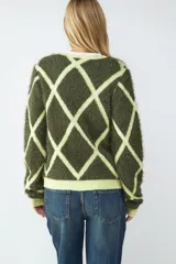 Cardigan de punto con cuello en V, manga larga y cierre frontal de botones. Presenta un estampado geométrico de rombos en contraste, con base verde oliva y líneas en verde lima. El tejido es de punto peluche.