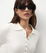 Cardigan de punto color blanco, con cuello camisero, cierre frontal de botones pequeños dorados, mangas largas y ruedo evasé con corte acinturado.