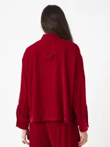 Camisa corta negra de terciopelo, de silueta cuadrada oversized, con bolsillo delantero y detalle en los puños y cuello con botón oro en forma de flor.