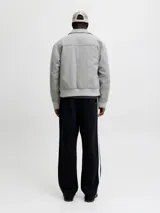 Campera bomber corta de paño gris claro, con cuello camisero, cierre frontal metálico completo y bolsillos laterales ribeteados. Presenta puños y cintura elasticados en rib acanalado.