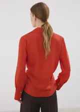Camisa de viscosa y poliamida color rojo, con cuello camisero, manga larga y diseño cruzado con lazo ajustable en la cintura.