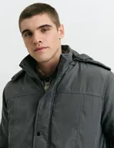 Campera Harrington de color verde oscuro, con cierre frontal de cremallera y solapa con botones a presión, cuello alto y bolsillos laterales.