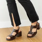 Sandalia de cuero vacuno con textura de reptil en color plateado, con diseño de punta cuadrada, cierre de hebilla lateral y taco cuadrado de madera.