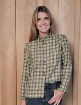 Camisa de manga larga con estampado de rayas verticales en tonos blanco y lila. Presenta cuello alto con volados, cierre frontal con doble botonadura y puños con volados.