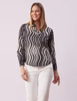 Blusa de gasa estampada en blanco y negro, marca Sioni. Tiene cuello con solapa y escote en V, mangas largas con puño fruncido.