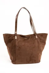 Bolso tipo tote bag color marrón, confeccionado en gamuza vegana con detalles de tiras y asas de hombro en cuero sintético brillante. Incluye una placa metálica pequeña con el logo de la marca en el frente.