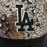 Gorro New Era 59Fifty de los Los Angeles Dodgers, con diseño camuflado en tonos marrón, beige y negro. Visera plana de charol negro y logo del equipo bordado en el frente.
