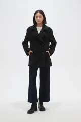 Chaqueta de corte holgado en color negro, con cuello solapa, cierre frontal con botones y bolsillos laterales.