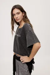 Remera gris de fit amplio, con mangas cortas y cuello redondo. Presenta efecto lavado y estampa frontal con aplicación de strass con la frase "fiesta mode on".