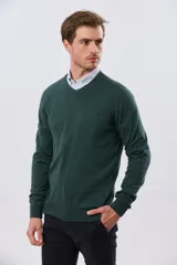 Buzo tejido de algodón color gris melange, de diseño clásico con escote en V, mangas largas y puños y ruedo acanalados. Cuenta con un pequeño bordado en el pecho.
