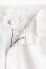 Pantalón jean de tiro alto en denim de algodón blanco, con diseño curvo de piernas con volumen y cinco bolsillos clásicos.