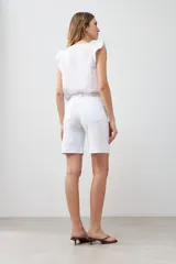 Bermuda de jean color blanco, con cinco bolsillos, corte a la rodilla y cierre frontal con botón y cremallera.