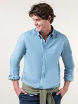 Camisa lisa de hombre color celeste, confeccionada en algodón con acabado vintage, corte regular fit, cuello button-down, cierre frontal de botones y logo bordado en el pecho.