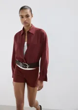 Camisa oversize color borravino, de manga larga con puños abotonados, cuello camisero, dos bolsillos de parche en el frente y cierre delantero con botones.