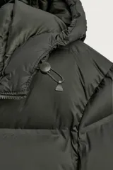 Cazadora puffer acolchada de corte relaxed fit color negro, confeccionada en tejido técnico repelente al agua. Cuenta con cuello subido, capucha ajustable con elásticos y cierre frontal con cremallera. Tiene bolsillos de vivo en la cadera, bolsillo interior y mangas largas con puños elásticos ajustables con abertura para el dedo pulgar.