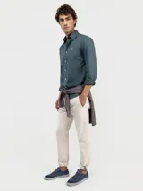 Camisa de hombre color azul, con cuello buttondown, cierre frontal con botones y logo bordado en el pecho. Presenta un acabado vintage logrado mediante el proceso de teñido en prenda.