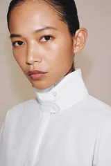 Camisa blanca de algodón de la colección ZW Collection de Zara, con cuello alto, mangas abullonadas por debajo del codo y cierre frontal con botones ocultos por solapa.