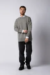 Sweater oversize de tejido de punto en color gris, con cuello redondo, puños y ruedo acanalados con detalles de desgaste. Presenta un diseño minimalista con logo tejido en la espalda.