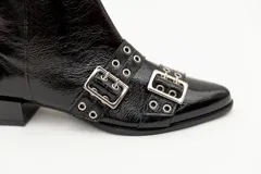 Botas cortas de cuero charol color negro, con aplique de hebillas con ojalillos y cierre lateral. Taco cuadrado bajo.