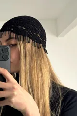 Gorro negro de crochet con flecos de cuentas colgantes en el borde frontal.