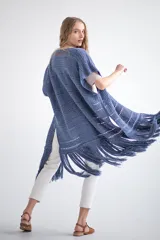 Chaleco largo de tejido de punto color azul verdoso, sin mangas y con flecos en el ruedo. Presenta calados con diseño geométrico.