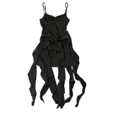 Vestido corto negro de corte asimétrico con escote en V y tirantes finos. Presenta un diseño con efecto desgastado y una sobrefalda con lazo frontal que aporta volumen y movimiento.