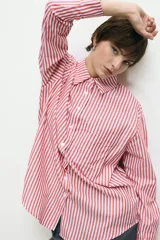 Camisa blanca de corte oversize, con cuello clásico, cierre frontal con botones y mangas largas.