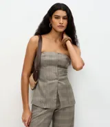 Blusa de sastrería sin breteles con estampado de cuadros, confeccionada en tejido estructurado con corte recto y bajo levemente evasé. Presenta un recorte delantero asimétrico y espalda con lastex para un ajuste preciso al cuerpo.